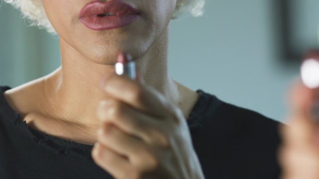 Transgender woman with sad expression holding a lipstick 