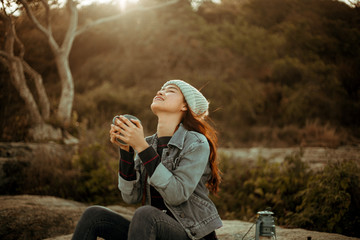 Asian woman drinking coffee on the mountain in sunset time camping travel concept