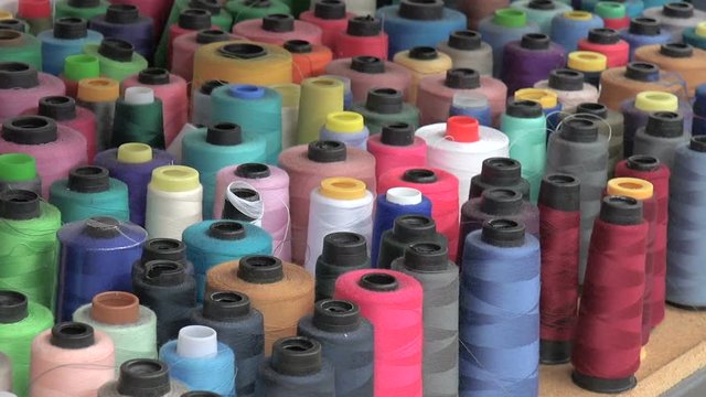 Multi-colored large spools of thread on a shelf