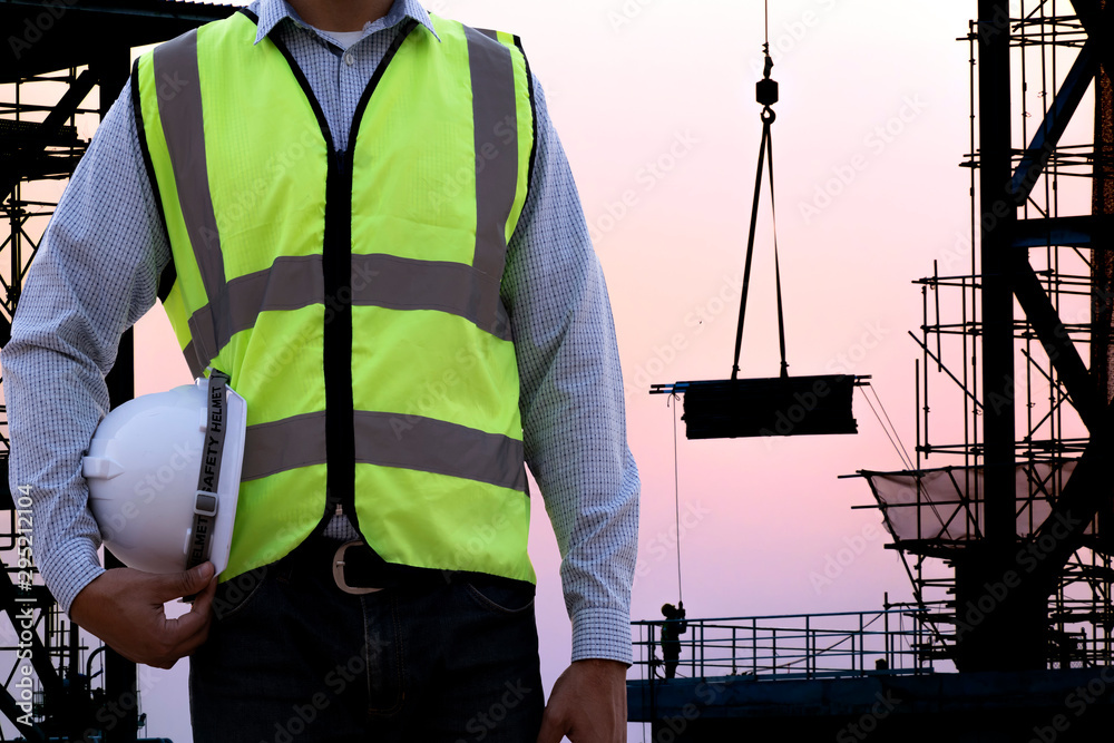 Wall mural safety officer holding hard hat with construction site.