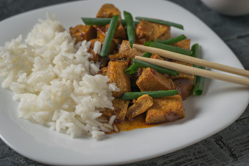 Chopsticks in a plate of rice and fried tofu cheese.