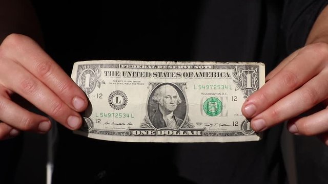Woman showing one dollar bill.