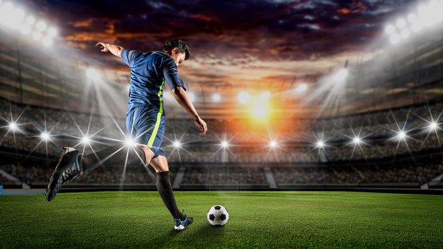 Soccer player kicks the ball on the soccer field.Professional soccer player in action. © sutadimages