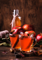 Hot mulled apple cider with with cinnamon sticks, cloves and anise on wooden background....