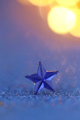 Christmas and New Year background. holidays wallpaper.Blue star macro on a blue glitter background with orange bokeh.Festive  shiny background