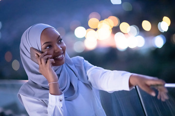 Young Muslim woman on  street at night using phone