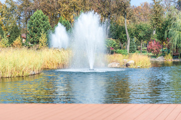 Naklejka premium Fragment of the park in Mezhyhiria near Kiev, fountains on the lake. Scenery of nature with sunlight. 