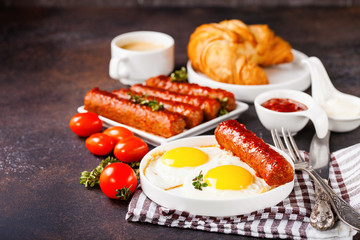 Breakfast - Fried eggs and meat sausages and sauces against a dark background. Selective focus. Copy space