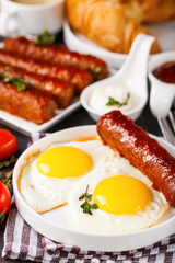Breakfast - Fried eggs and meat sausages and sauces against a dark background. Selective focus. Copy space