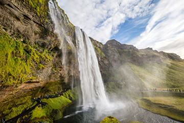 Seljalandsfoss waterfall drops from cliffs that allow people to walk behind the falls in Southern Iceland