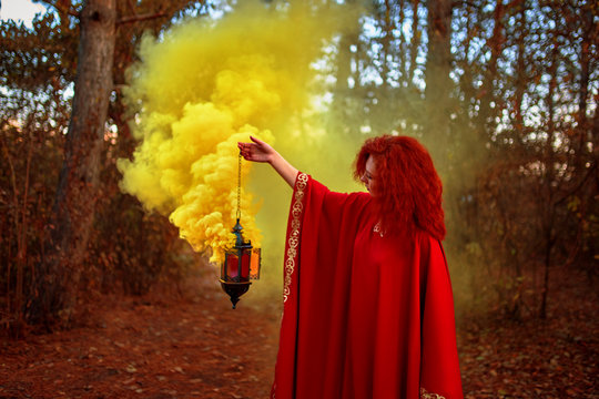 Smoke screen in the woods. Young redhead woman in the forest. Around her a lot of smoke