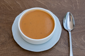 Vegetable cream soup with tomato, potato, squash in a white bowl, closeup