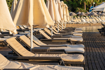 Empty sunbeds and parasols on morning, by the sea. Sand beach in luxury hotel resort near sea. Beautiful morning seascape. Turkey