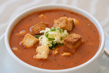 Tomato soup with croutons, cheese and fresh parsley, closeup