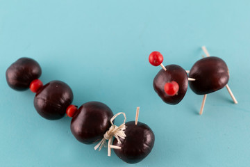 Creative natural children toys handmade from chestnuts and acorns on marine blue background. Concept of Chestnuts animal figurines.