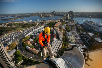 Abseiler wearing full body safety harness  working at height hanging abseiling from high rise...