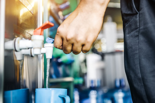 Man pressing the water dispenser head of water veding machine in the factory floor