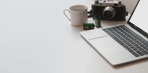 Cropped shot of minimal workspace with laptop computer and camera on white table table