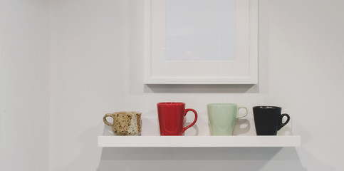 Fototapeta na wymiar Cropped shot of wall shelf with coffee cups and mock up frame