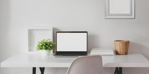 Minimal workspace with open blank screen laptop computer with mock up frame and office supplies
