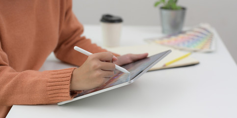 Cropped shot of young female working on her project with tablet