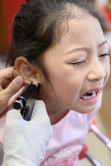 Adorable little Asian girl having ear piercing process. - 295228346