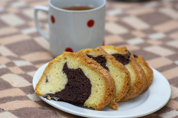 Gugelhupf on white plate on picnic blanket, very tasty edible two-colored Czech sweet cake called babovka, sliced ready to eat