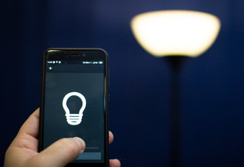 Smart home: man controlling lights with app on his phone.
