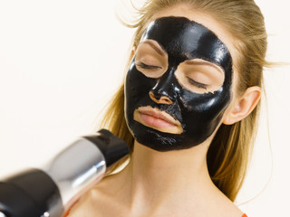 Girl drying peel-off black mask on face