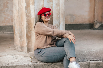 Plus zise model wearing sweater and beret posing on the city street