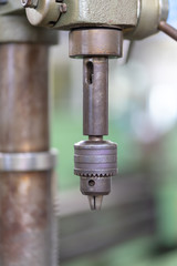 Drill in the chuck of a drilling machine in a motorcycle workshop