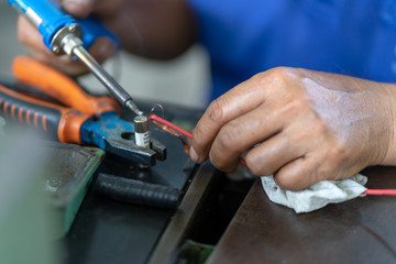 Soldering iron soldering a wire to an electrical component with smoke coming of it  lying on top of coloured wires