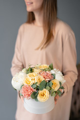 Small Beautiful bouquet in a round box. Bunch of mixed flowers in woman hand. Floral shop concept. Flowers delivery. White peonies