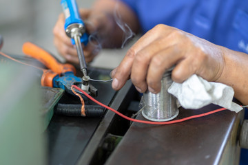 Soldering iron soldering a wire to an electrical component with smoke coming of it  lying on top of coloured wires