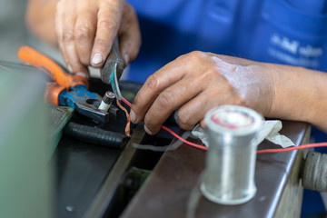 The man technician hand hold Knife a router to strip electrical wire stripper in electronic parts.