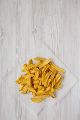 Homemade french fries with salt on a white wooden background, overhead view. Flat lay, top view, from above. Copy space.