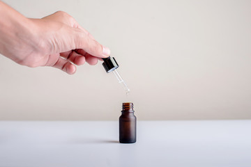 Close up of hands used serum dropping on her bottle with white background.