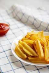 Homemade french fries with sour-sweet sauce on a white plate, side view. Close-up.