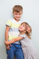 Cute happy siblings hugging cuddling feeling love and connection on a gray background. children good relationships