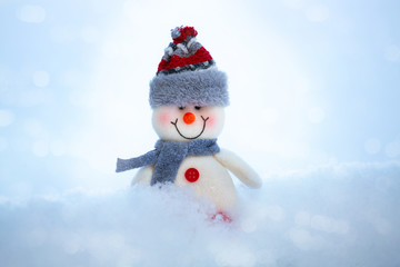 On the snow is a happy funny toy snowman. The snowman is wearing a fur hat and scarf. The concept of winter, Christmas, New year. Copy space. horizontal orientation.