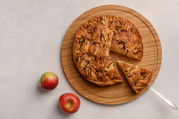 Cornish apple pie with a cut piece on the shoulder blade top view on rustic style white background. Next to two apples. Copy space for your text