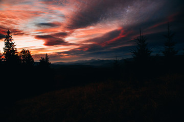 Amazing sunset in the mountains. The sky is covered with clouds of red