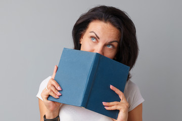 Fototapeta premium Brunette woman holding a book in her hands over a grey background