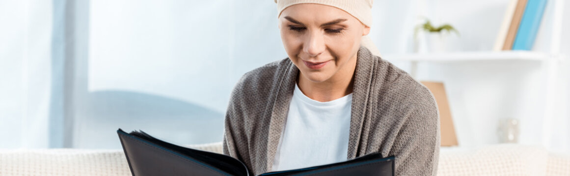panoramic shot of sick woman with head scarf holding photo album