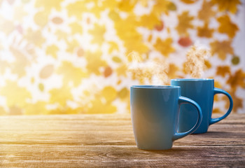 Two cups of hot coffee cup on a autumn leaves background