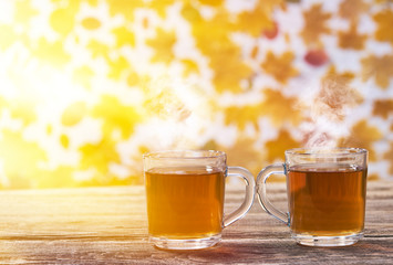 Autumn composition with hot tea.two glass cup tea on a wooden board on a autumn background