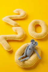 Happy New Year 2020. Number 2020 knitted from yarn and gray toy mouse symbol of year on bright yellow background, cheese color. Flat lay, top view, copy space