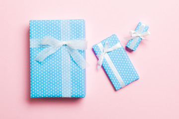 Gift box with white bow for Christmas or New Year day on pink background, top view