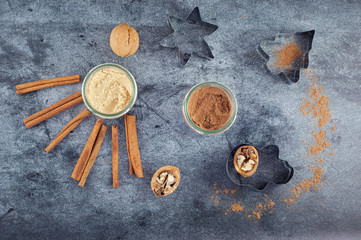 Baking ingredients. Cinnamon, nutmeg, ginger, walnuts, cookie molds, top view on a gray background.