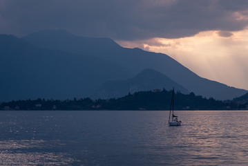 Fototapeta na wymiar Un coucher de soleil et un voilier sur le Lac Majeur. Un bateau voyage sur un lac.